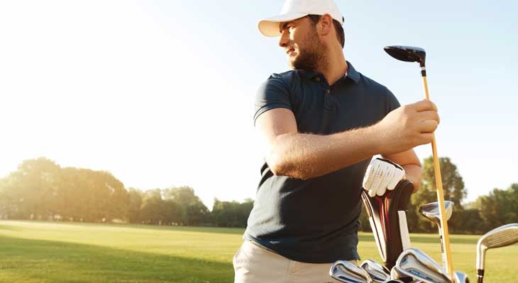 Photo of a man taking a golf club out of a bag on a sunny day