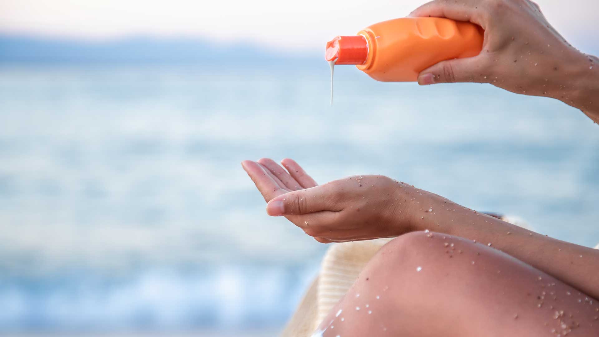 Photo of a person at the beach applying sunscreen