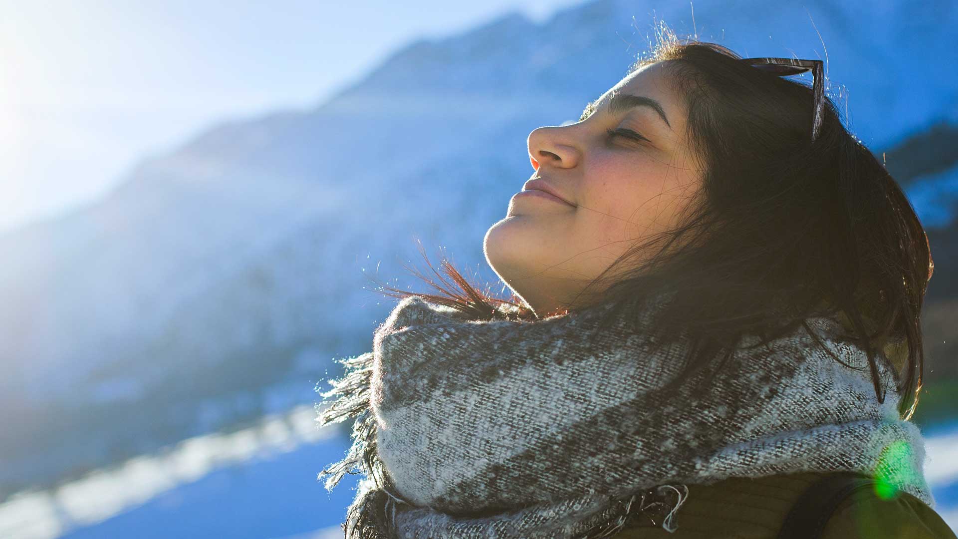 A woman standing with her face pointed towards the Winter sun